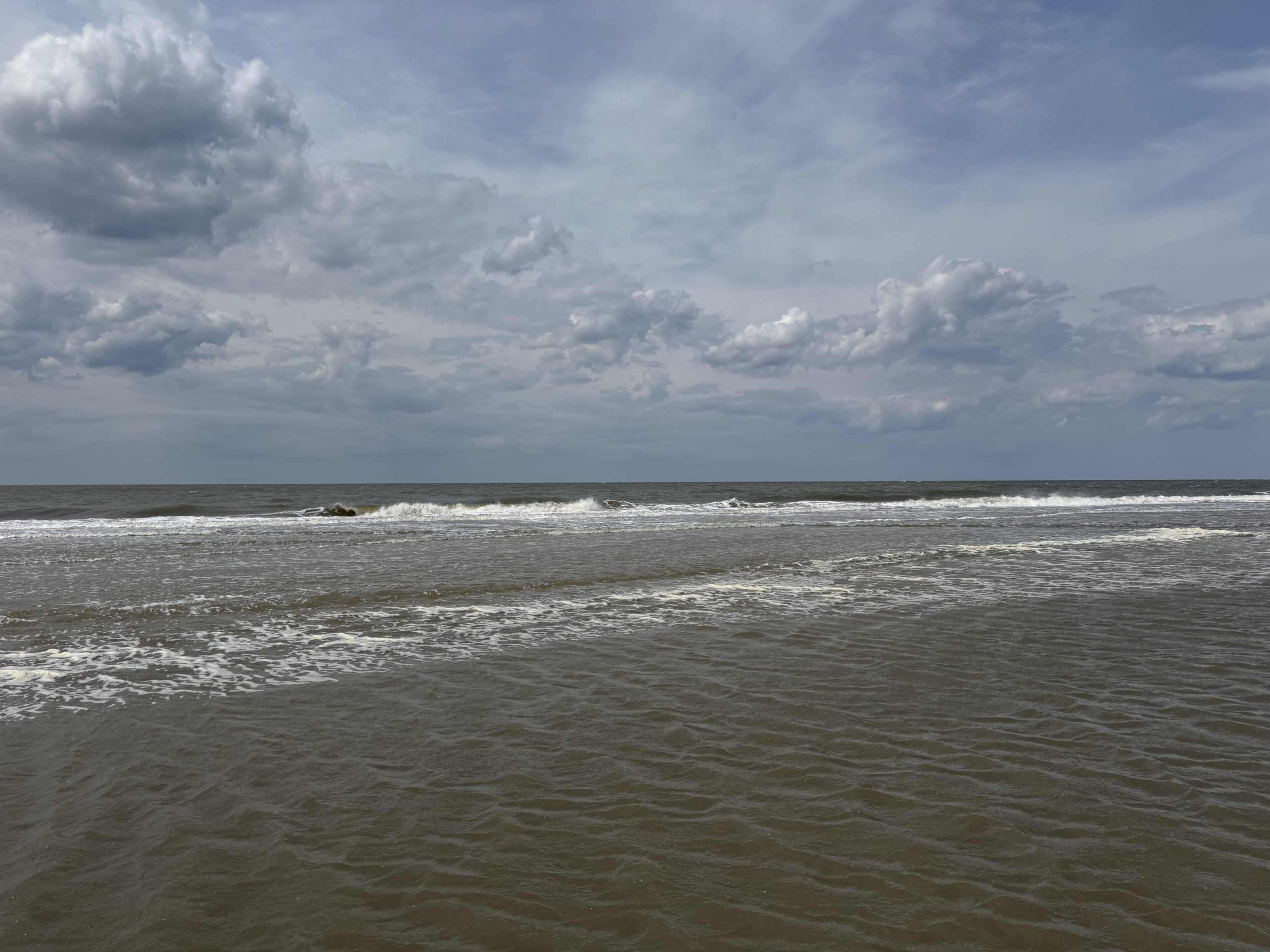 Blick auf die aufgewühlte Nordsee mit heranrollenden Wellen und schaumiger Gischt an einem wolkigen Tag.
